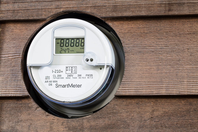 Digital electricity meter mounted on a wooden wall.